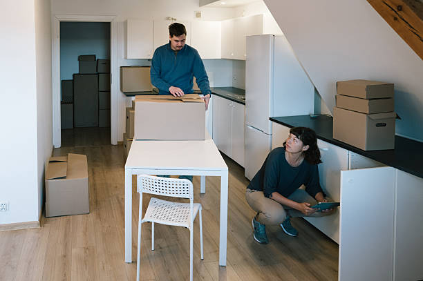 istock Relocation: A young woman checks the kitchen cabinets with a touchpad while a man packs boxes 2229900710