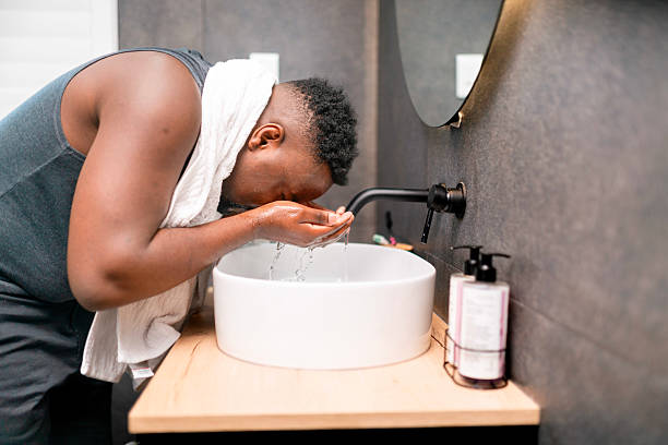 istock Man Washing Face at Sink in Modern Bathroom Interior 2229901073