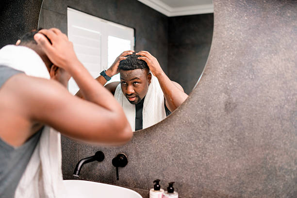 istock Man Standing in Front of Mirror Examining Hairstyle Post-Shower 2229901080