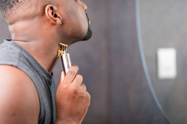 istock Man Grooming Beard with Electric Trimmer in Modern Bathroom 2229901114