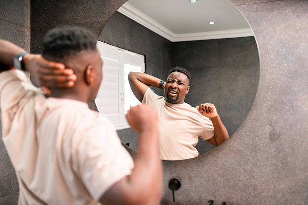 istock Man Stretching and Yawning While Reflecting in Bathroom Mirror 2229901165