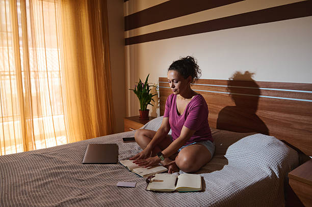 istock Woman Sitting on Bed Writing in Notebook During Daytime 2229902490