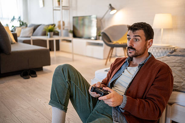 istock Young man playing video games at home and experiencing surprise 2229902552