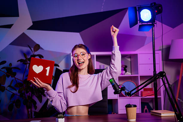 istock Young female content creator streaming in a stylish home studio with a glowing neon background showcasing modern media tools 2229903059