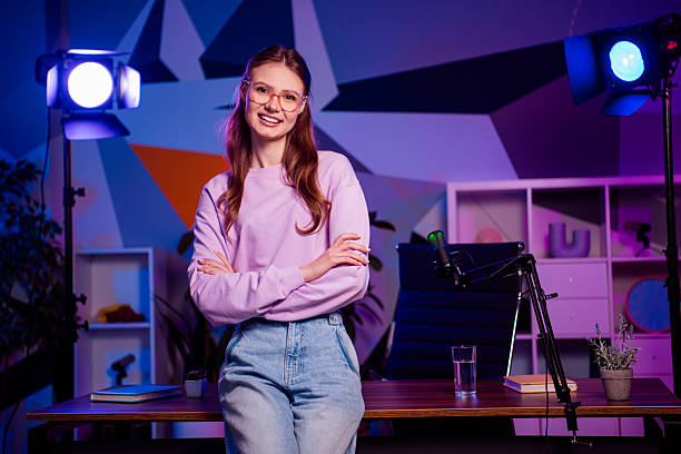 istock Professional female content creator working in a modern neon-lit office studio with a microphone and camera equipment 2229903080