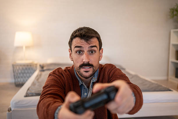 istock Excited man playing videogames at home in his bedroom 2229903089
