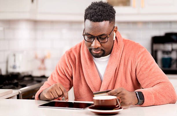 istock Man in Cozy Robe Shopping Online While Relaxing at Home Kitchen 2229903373