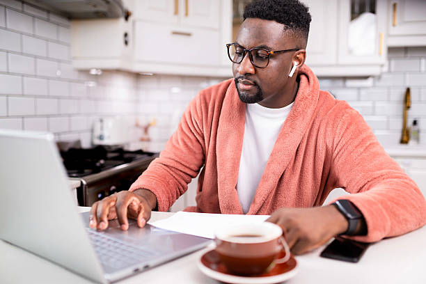 istock Man Wearing Airpods Working on Laptop at Home in a Cozy Kitchen Setting 2229903380
