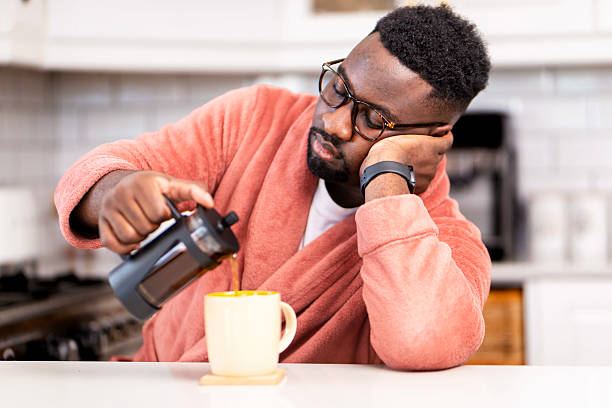 Man Pouring Coffee in Morning Kitchen While Feeling Sleepy