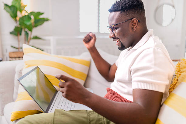 istock Excited Young Man Celebrating Success While Using Laptop at Home 2229903617