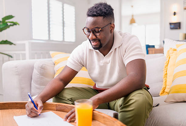 istock Smiling Man Writing Notes at a Cozy Home Desk with Orange Juice 2229903626