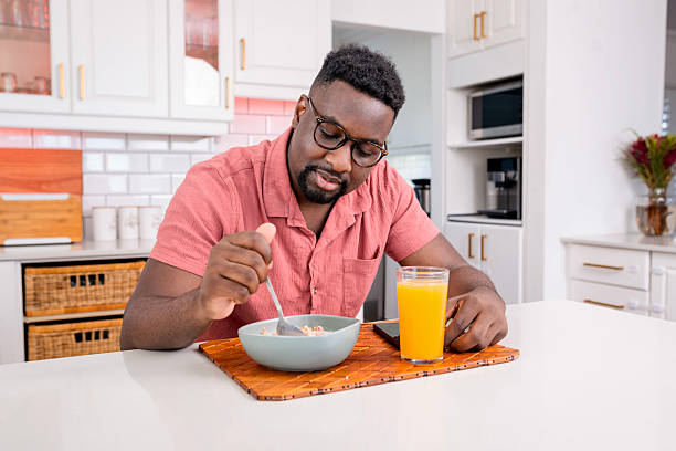 Man Eating Breakfast in Modern Kitchen With Focused Expression and Orange Juice