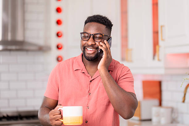 istock Smiling Professional Talking on Phone and Holding a Cup in Modern Kitchen 2229904000