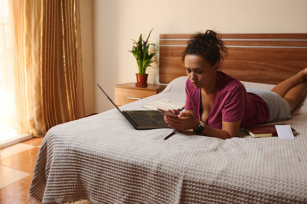 istock Young Woman Using Technology on Bed in Cozy Well-Lit Room 2229904412