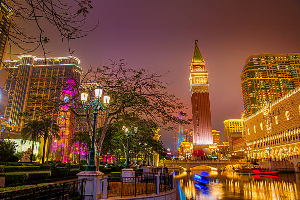 Taipa, Macau on 10 JANUARY 2024. The Venetian Macao's stunning facade under a cloudy sky, framed by lush trees at night. A grand Venetian-style building with a tall clock tower, creates a captivating scene.