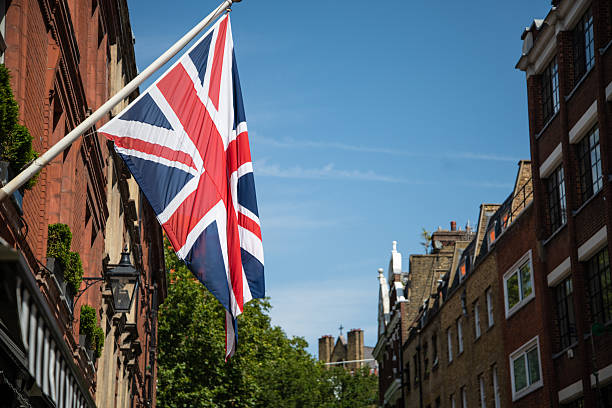 istock Union Jack flag on a flagpole against a clear blue sky 2229905506