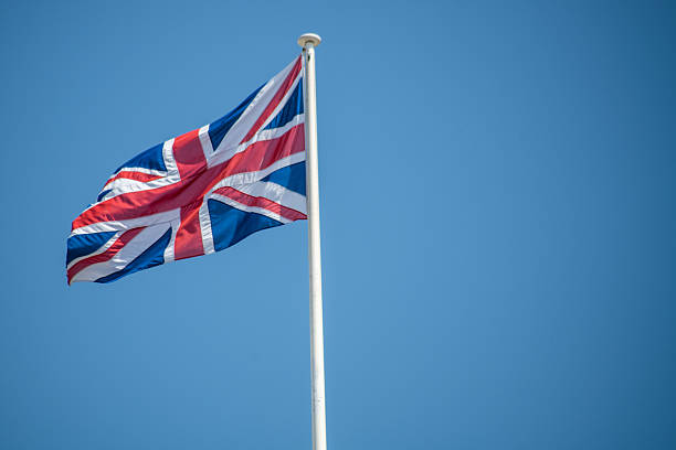 A strong gust of wind captures the Union Jack as it waves gracefully against a clear blue sky, symbolizing unity and pride in British culture on a bright day.