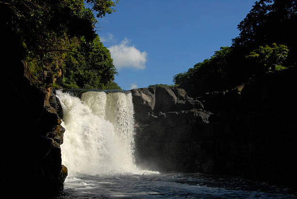 Tropical waterfall in Mauritius cascades between volcanic rocks into a dark pool