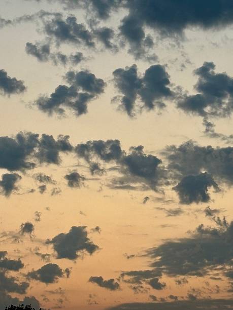 istock Dramatic sky at sunset with scattered dark clouds over a warm orange and blue background. A peaceful, moody atmosphere perfect for nature, weather, and scenic themes in creative projects. 2229909361