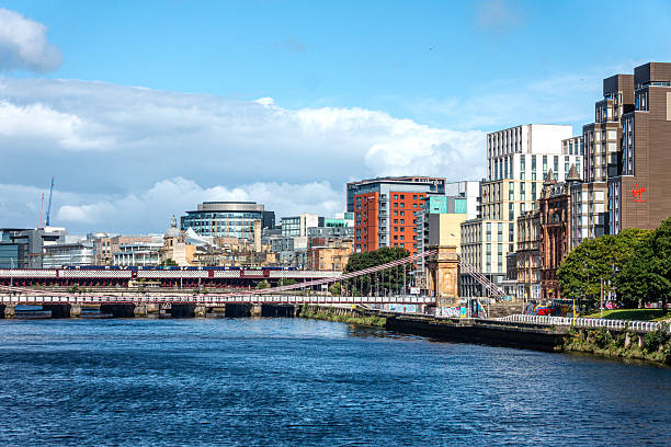 View over the River Cl.yde in central Glasgow, Scotland, towards South Portland Street Suspension Bridge (pedestrians only) and the Caledonian Bridge, over which a train is passing. Some of the buidlings on the north of the river can be seen.