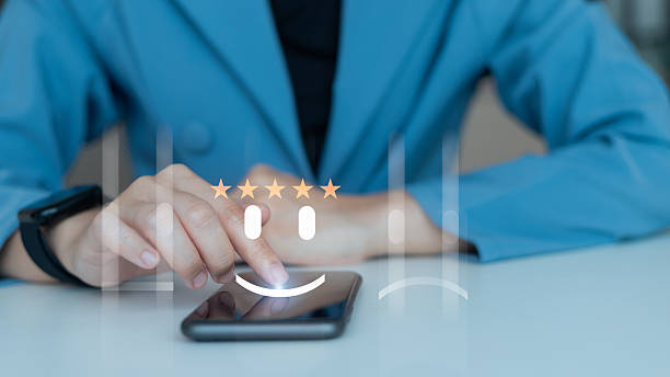 istock Customer using smartphone to give five-star rating with happy face icon on virtual screen, concept of positive feedback, service review, and satisfaction 2229913807