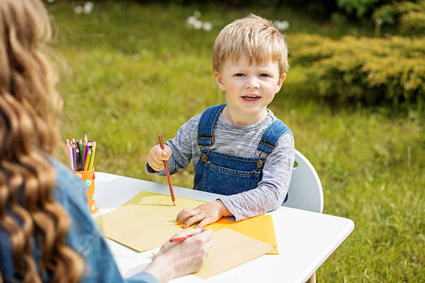 istock Smiling boy drawing with colored pencils outdoors 2229915072