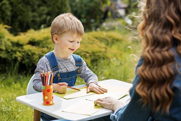 istock Smiling boy drawing with colored pencils outdoors 2229915083