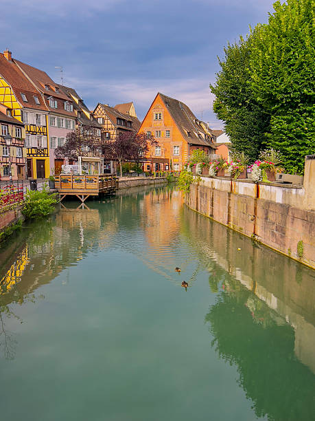 On a bright summer day, the charming canals of Colmar wind through colorful half-timbered houses and cobblestone streets, reflecting the historic beauty and romantic ambiance of this picturesque Alsatian town