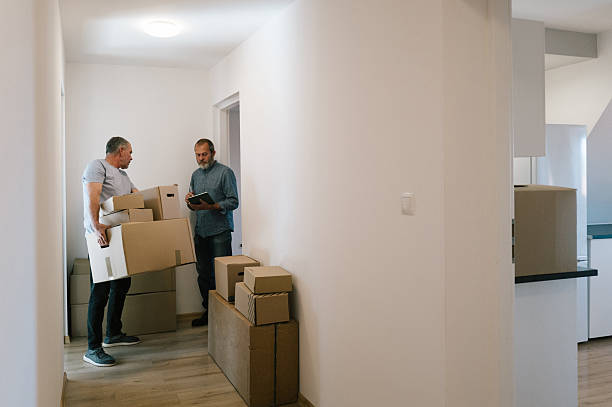 istock relocation: A man carry a box while another man tries to connect to the internet using a touchpad 2229920738