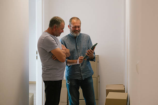 istock Relocation: two men discussion the internet connection with a touchpad into a new empty apartment 2229920880