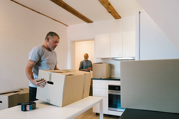 istock Moving: A man carry a box while another man tries to connect to the internet using a digital tablet into the kitchen of an empty flat 2229921017