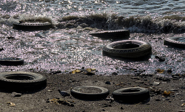 discarded old used tires in water sea ocean pollution dirt garbage refuse car truck rubber filth cleanup restore restoration wave beach cleanup brooklyn new york narrows hudson river