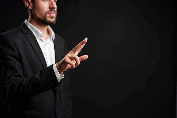 istock Businessman presenting an idea with hand gestures in a formal suit against a dark background 2229922530