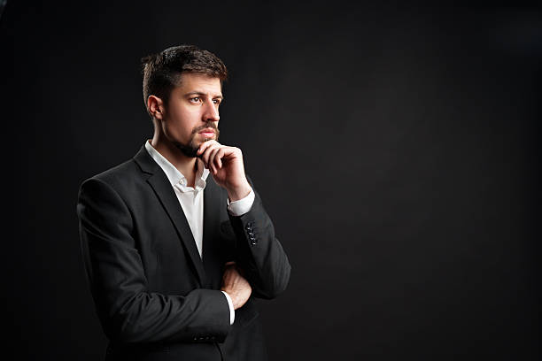 istock Professional man in a black suit contemplating ideas in a studio setting 2229924539