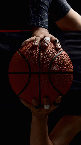 istock Two hands gripping basketball with taped fingers in dramatic light 2229927566