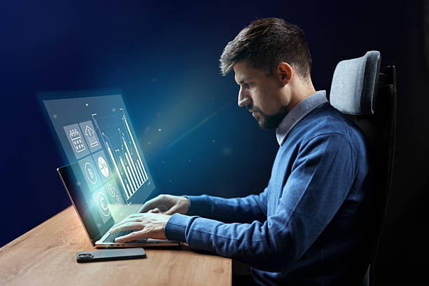 istock Professional man works on computer displaying financial data and graphs in a modern office setting during evening hours 2229927597