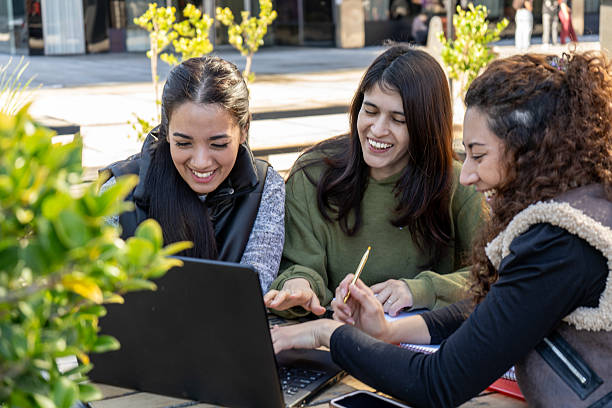 istock University students collaborating on a project using laptop outdoors 2229928105
