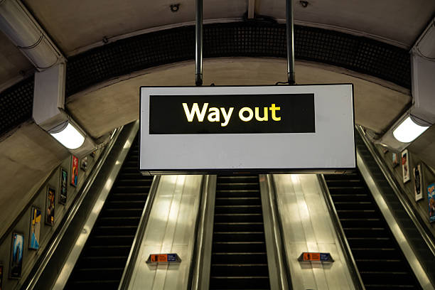 Way Out sign on the London Underground with escalator in the background, symbolising exit, travel direction, and iconic UK transport design.