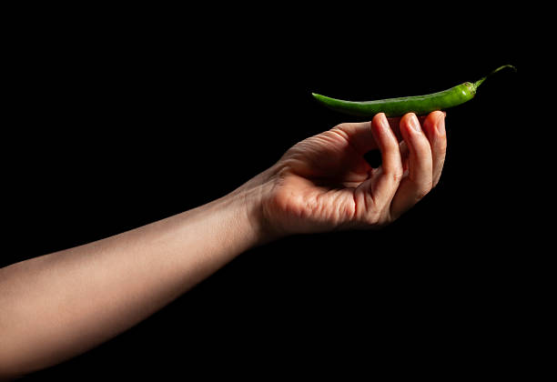 green long chili pepper in hand on black background