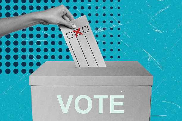 Voting process at a polling station with a hand inserting a ballot into a box during an election