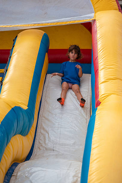 istock Young girl enjoying inflatable slide at summer event 2229940352