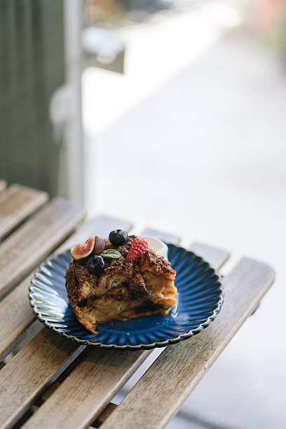 Slice of bread pudding topped with fresh fruits on blue plate.