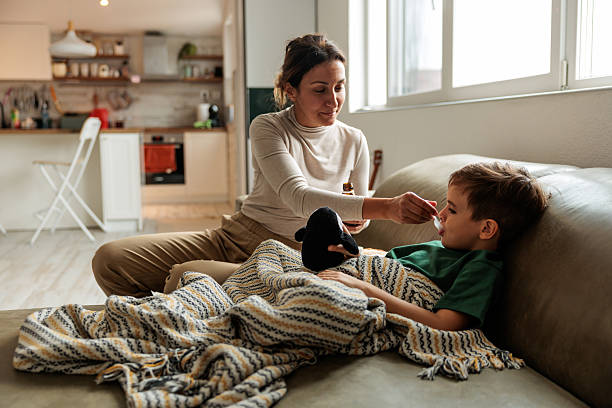 istock Sick Boy Taking Syrup from Mother’s Hand 2229942911