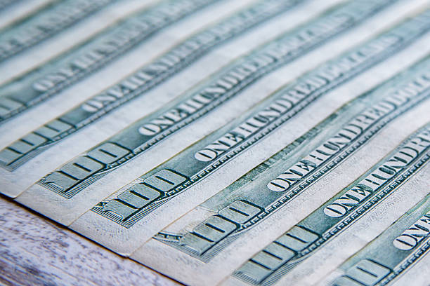 istock Hundred-dollar bills close-up spread on table with focus on number one hundred and word hundred 2229945288