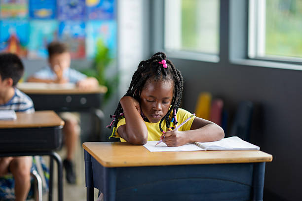 istock Young Girl Concentrating On Writing in a Classroom Setting 2229948354