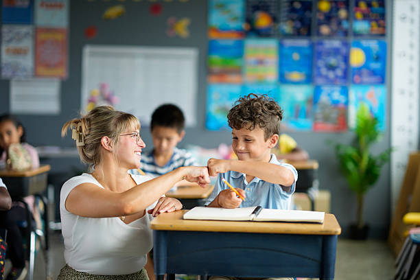 Teacher Encouraging Student in Classroom with Learning Activity and Positive Support stock photo