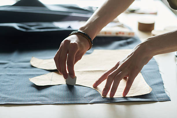 istock Young Adult Caucasian Man Marking Fabric Pattern While Tailoring Garment 2229951191
