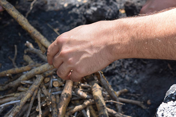 istock Man's hands making campfire in the wild. Tourist man's hands kindle a fire in the mountains. Concept of scout, research, travel and survival in nature. Cooking and heating in forest. Danger in forest. 2229952533