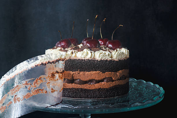 istock black forest cake on a glass cake stand against a black background. 2229952673