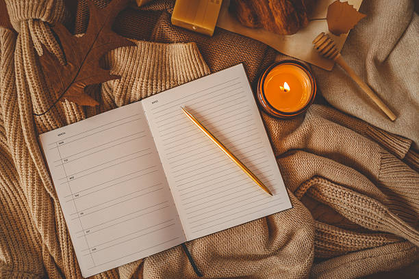 Cozy autumn-themed flat lay with an open weekly planner showing blank days on the left page and a lined âNotesâ section on the right. A golden pen rests diagonally across the notes page